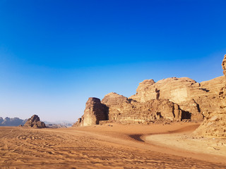 Fototapeta na wymiar Safari trip on a pick-up truck around the Wadi Rum desert on a sunny day with a blue sky. Off-road cars that left their tire tracks on the sand among rocky mountains in the Arabian desert. 