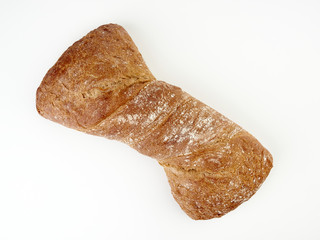 Fresh dark ciabatta lies on a light background.