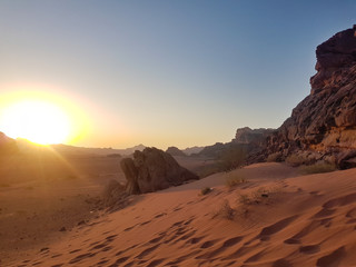 Fototapeta na wymiar Sunset in Wadi Rum desert. Sundown and rocky mountains. Safari ride on pick up trucks. Peaceful desert landscape. One minute before sundown.