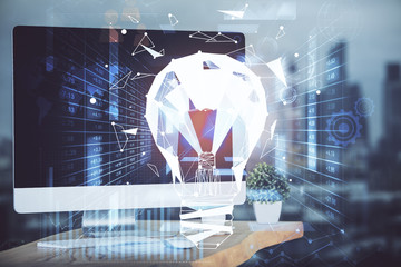 Computer on desktop in office with bulb icon hologram. Multi exposure. Concept of idea.