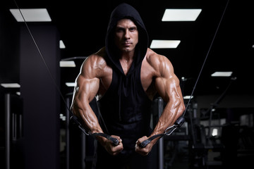 Fototapeta na wymiar Handsome muscular sexy man posing in gym. Tanned athlete.