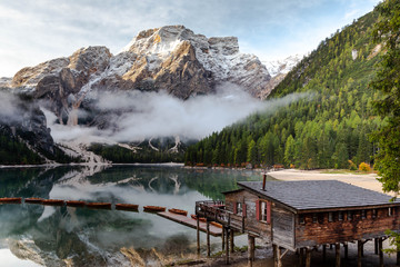 Lago di Braies or Lake Braies in the Dolomites. Lake is surrounded by mountains. Wooden boat house on the shore and the boats floating on the water surface. Photo in bright colors. Italy, South Tyrol.