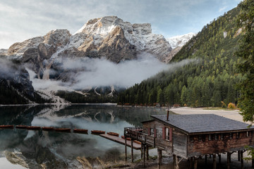 Lago di Braies or Lake Braies in the Dolomites. Lake is surrounded by mountains reflected in the water. A woden boat house on the shore and the boats floating on the water surface. Italy, South Tyrol.
