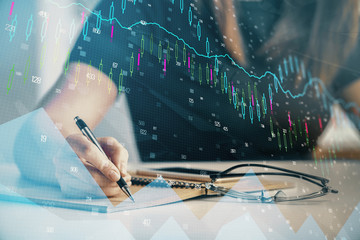 Multi exposure of woman's hands making notes with forex graph hologram. Concept of technical analysis.