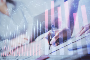 A woman hands writing information about stock market in notepad. Forex chart holograms in front. Concept of research. Double exposure