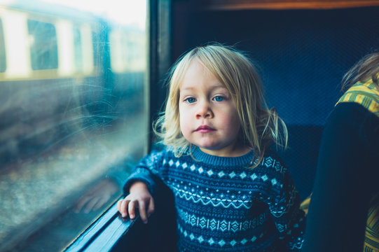 Little toddler on a train looking out the window