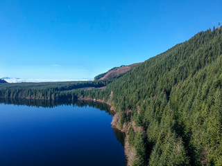 Fototapeta na wymiar Rarely seen beautiful aerial photographs of Calligan Lake in Washington State with green mountainside open vistas clouds blue sky and shoreline on a warm autumn day.
