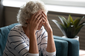 Elderly woman covered face with hands crying feels desperate