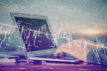 Double exposure of stock market graph with man working on laptop on background. Concept of financial analysis.