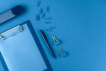 Classic blue colored top view photo of scattered stationery