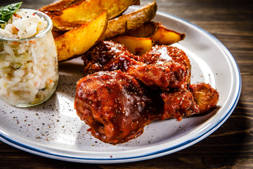 Barbecue chicken drumsticks with baked potatoes and coleslaw