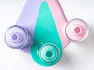 Pastel color spilled nail polish bottles over white