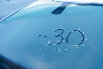 Parked car with hoarfrost on the windshield and the inscription 
