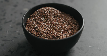 flaxseed in black bowl on terrazzo countertop with copy space