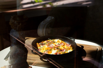 fried eggs with ham in a skillet. restaurant breakfast.
