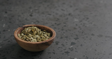 pumpkin seeds in olive bowl on terrazzo countertop with copy space