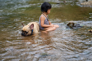 cute asian girl playing with her lovely french bulldog at stream in nature.