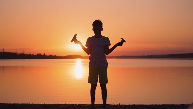 Little boy with paper plane. Beautiful sunset. Origami.