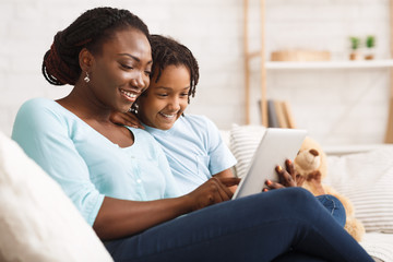 Happy black family spending time together using tablet