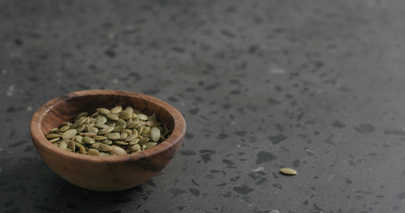 pumpkin seeds in olive bowl on terrazzo countertop with copy space