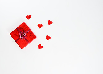 Fototapeta na wymiar Gift in red packaging with hearts on a white background. Horizontal orientation, copy space, top view.