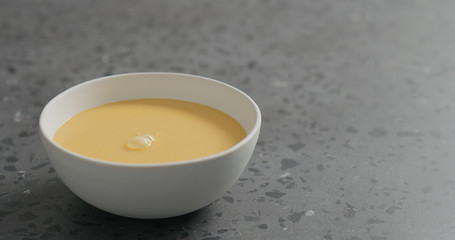 pumpkin cream soup in white bowl on terrazzo countertop