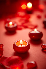 Romantic dinner decoration. Red candles, flower petals, on the table
