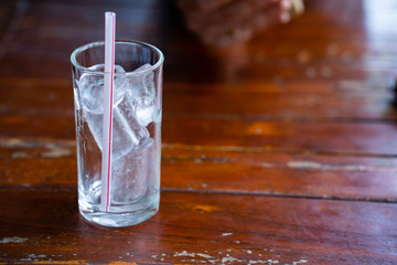 Glass of ice cube on wooden table.