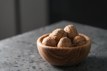 inshell walnuts in olive wood bowl on terrazzo countertop