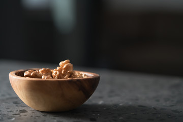Walnuts in wooden bowl on terrazzo countertop with copy space
