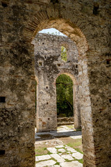 Fototapeta na wymiar Church arcs, framed view. Beautiful warm spring day and archeological ruins at Butrint National Park, Albania, UNESCO heritage. Travel photography with fresh green flora and clear blue sky