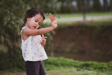 Cute little girl playing at park with flower.