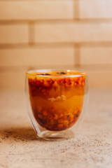 Sea buckthorn tea with orange in a glass cups with fresh sea buckthorn berries and leaves. Herbal vitamin tea.