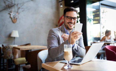 Handsome business man receiving a happy message on his cell phone