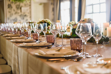 Elongated table with all the cutlery elegantly arranged and beautiful centerpieces ideal for decorating a wedding.