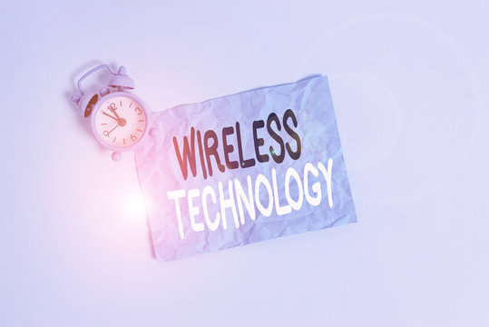 Conceptual hand writing showing Wireless Technology. Concept meaning a technology that allows wireless communication Metal vintage alarm clock crush sheet sky colored background