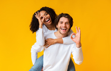 Happy interracial couple showing ok gesture and having fun together