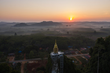 Fototapeta premium Beautiful sunrise with pagoda on the top of rock and tree with fog at Khao Na Nai Luang Dharma Park,Surat thani province,Thailand