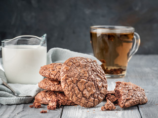 Brownie cookies on a wooden table with tea and milk. Copy space.