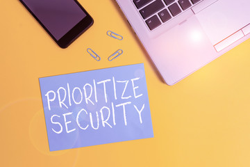 Text sign showing Prioritize Security. Business photo showcasing designate security risk as more important to solve Trendy open laptop smartphone small paper sheet clips colored background