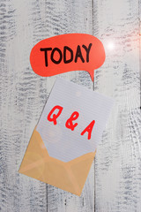 Text sign showing Q And A. Business photo text a period of time or an occasion when someone answers questions Front view open envelop speech bubble paper sheet lying wooden background