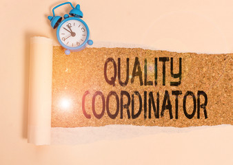 Writing note showing Quality Coordinator. Business concept for monitor and improve the quality of analysisufactured products Alarm clock and torn cardboard on a wooden classic table backdrop