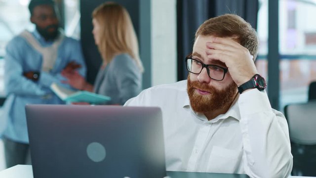 Close up view of tired sad business man touching head looking at the watch working hard on laptop upset exhausted young office work worried sleepy stressed frustrated employee corporate computer