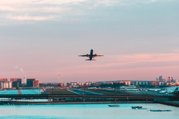 Airplane taking off from London city airport at sunset - obrazy, fototapety, plakaty