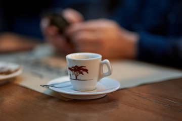 Coffee cup and man using cellphone