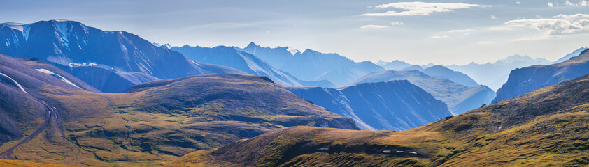 Panoramic view, mountain landscape. Treeless hills, peaks in a blue haze. Travel and vacation in the mountains.