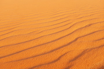Bright orange desert sand ripples for a warm and vibrant summer background