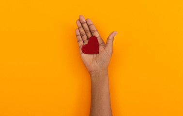 Red felt heart in opened palm of black woman