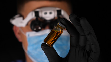 Laboratory worker scientist laboratory assistant tests chemicals for reactions in flask,...