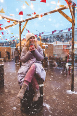 Girl walking in the Christmas market, a fair decorated with holiday lights in the evening. The mood...